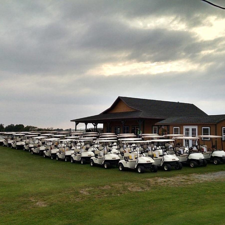 more than 30 golf carts lined up in front of a clubhouse
