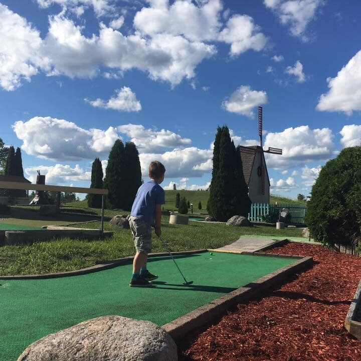 little kid playing putt putt golf on a sunny day