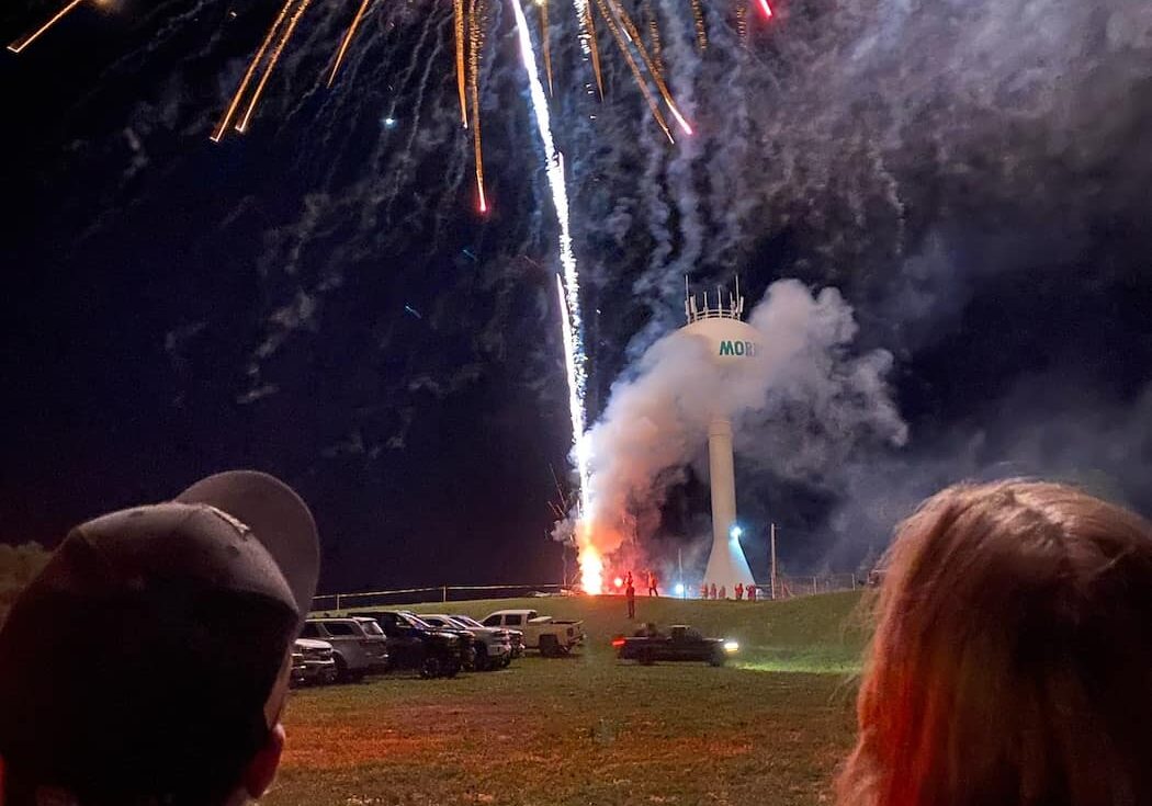 couple watching fireworks with water tower in the background
