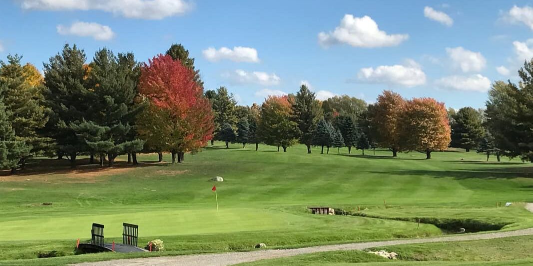 golf course on a sunny day with fall leaves on the trees