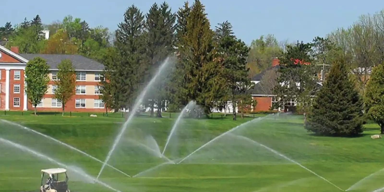sprinklers watering a golf course lawn